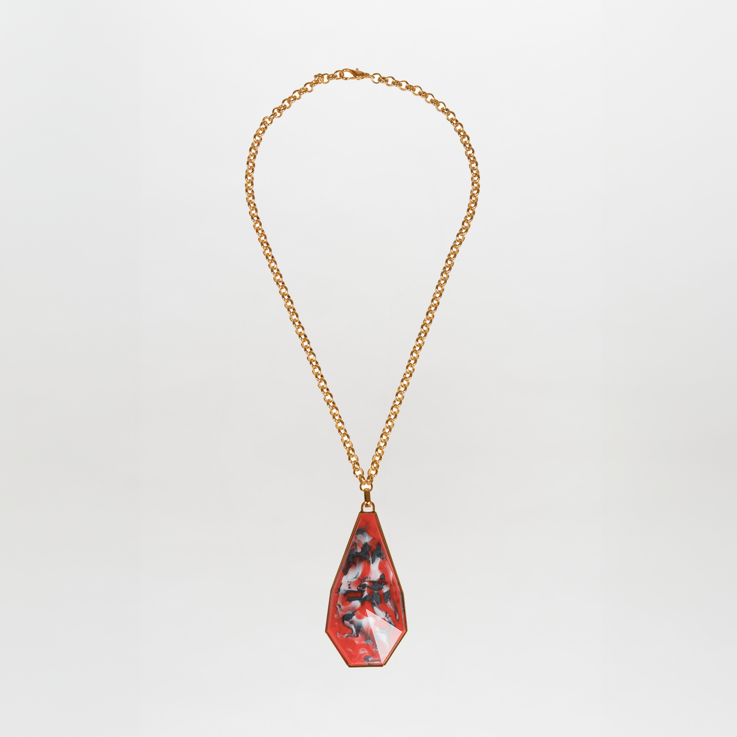 The Ascoli Necklace is a gold chain accessory with a triangular pendant showcasing a marbled red, black, and white pattern made from Petralux® fantasy stone.
