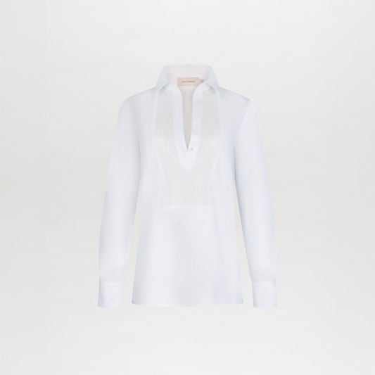 The Bega Blouse is a white, long-sleeve cotton top with a collar and textured lace detailing on the chest, shown against a plain white background.