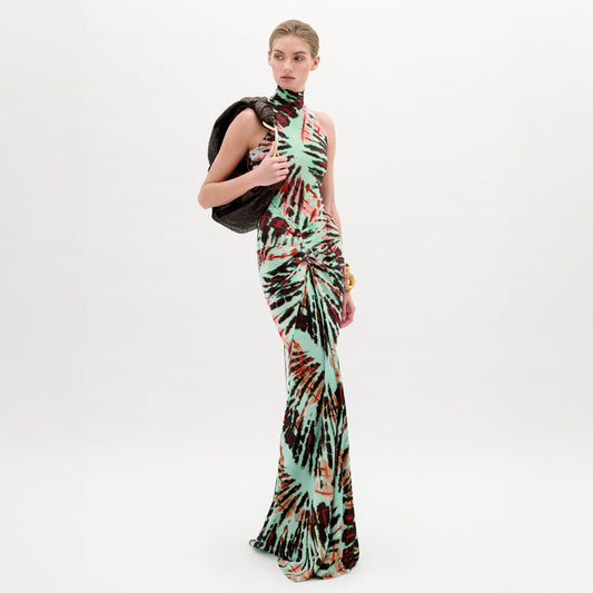 A woman wears the Frances Dress, a sleeveless, slim-fit maxi with a high neckline, holding a dark jacket over her shoulder against a plain white background.