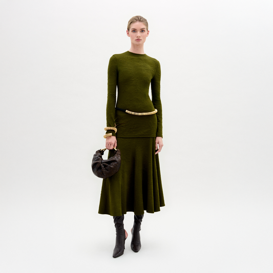 Woman wearing a green outfit with a skirt and sweater on a white background