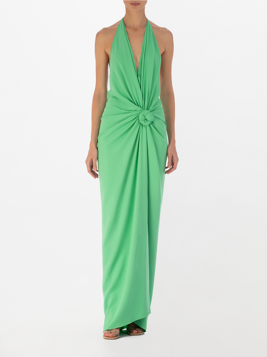 A woman in a Jazmin Dress Seafoam with a halter neckline and a knotted design at the waist, standing against a white background.