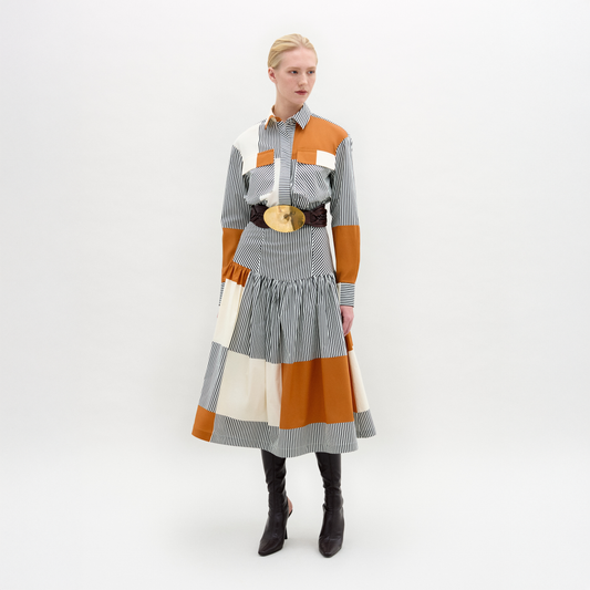 Woman wearing a patchwork dress with orange, gray, and white colors on a white background