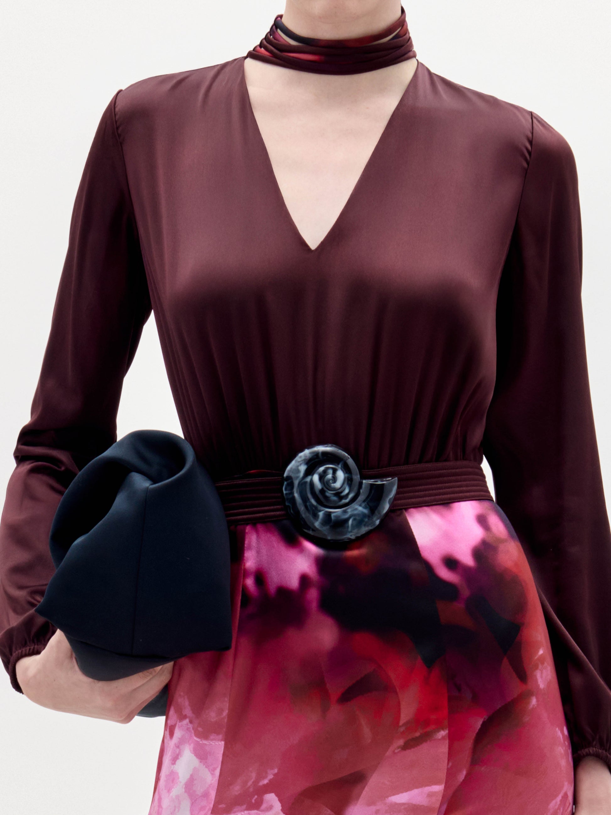 A woman stands against a plain background wearing the Jailyn Dress, black heeled sandals, and holding a black clutch.