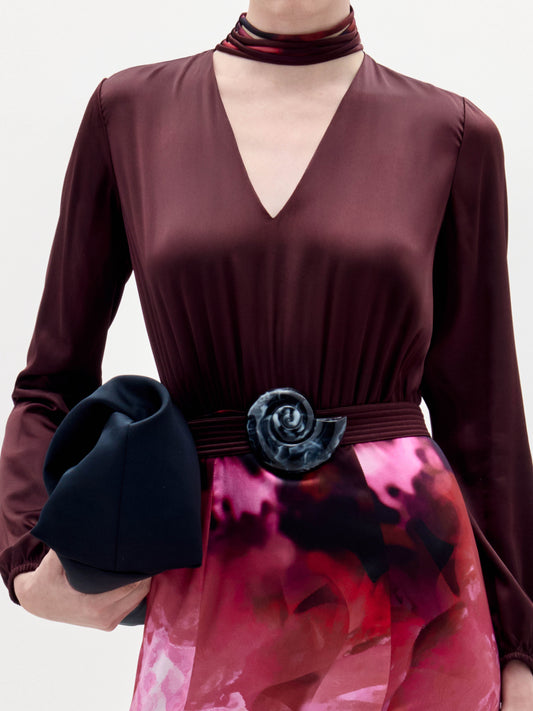 A woman stands against a plain background wearing the Jailyn Dress, black heeled sandals, and holding a black clutch.