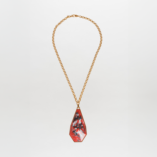 The Ascoli Necklace is a gold chain accessory with a triangular pendant showcasing a marbled red, black, and white pattern made from Petralux® fantasy stone.