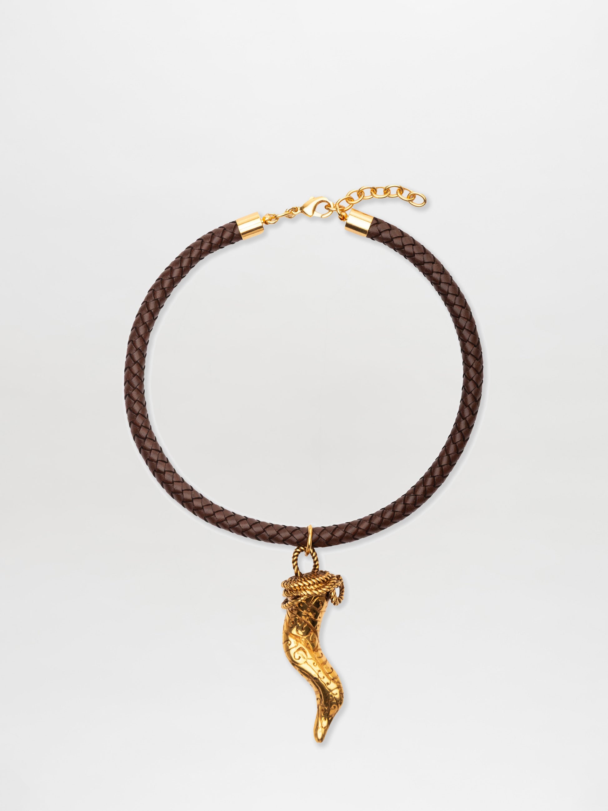 The Dominica Chocker is a brown leather choker featuring a gold clasp and an ornate cornicello pendant, crafted from fine Italian materials and elegantly showcased at the center.
